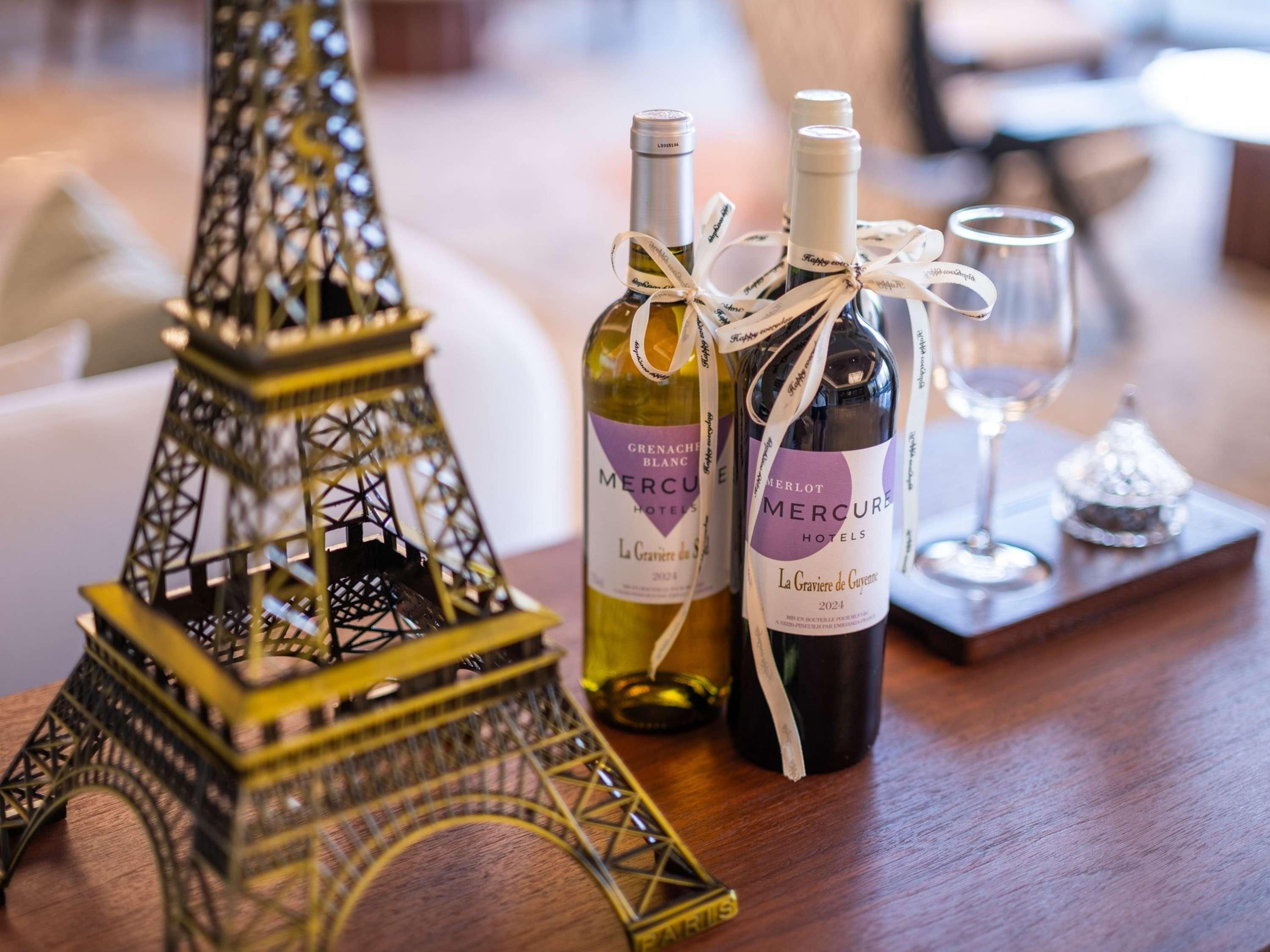 A table with two bottles of wine, a glass, and a miniature Eiffel Tower.