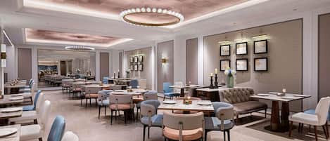 A spacious hotel dining area with multiple tables and chairs, a modern ceiling design, and framed artwork on the walls.