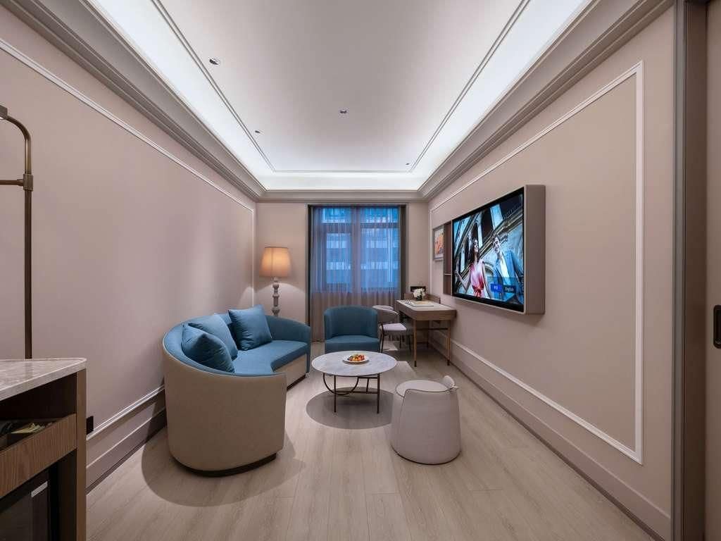 A modern living room with a sofa, chairs, a coffee table, and a flat-screen TV mounted on the wall.