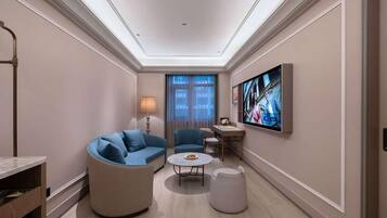 A modern living room with a sofa, chairs, a coffee table, and a flat-screen TV mounted on the wall.
