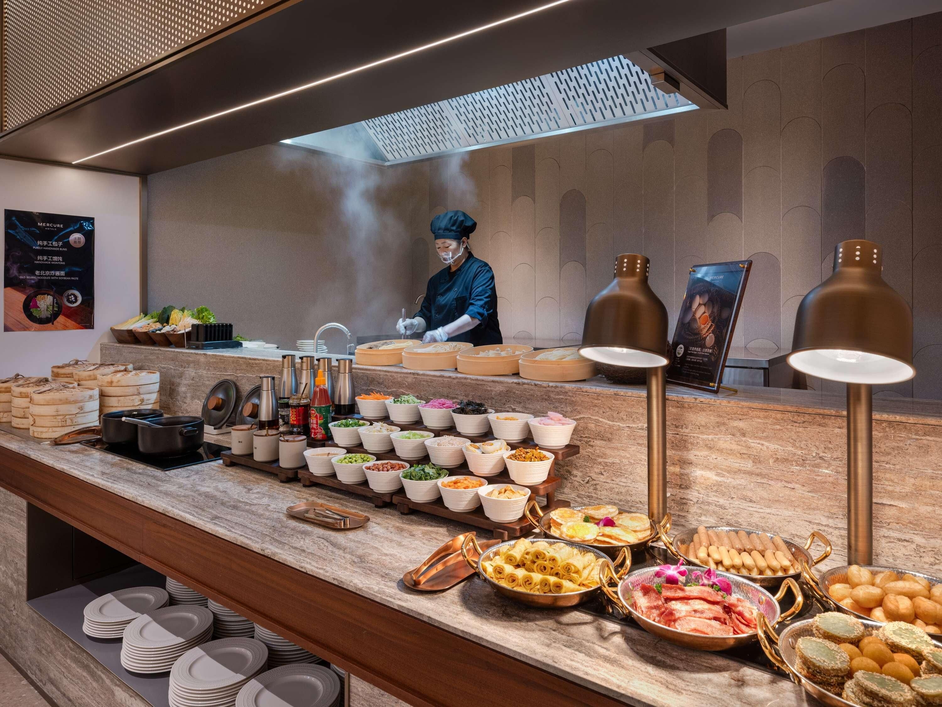 Montaje de bufé con diversas opciones de comida y un chef preparando alimentos.