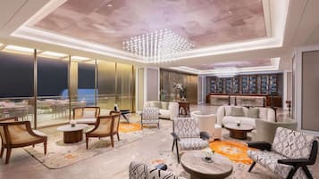 A spacious lounge area with seating, a bar, and a view of the city.