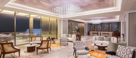 A spacious lounge area with seating, a bar, and a view of the city.