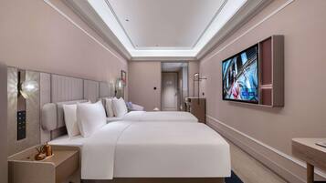 A modern hotel room with a large bed, a flat-screen TV, and a bedside table.