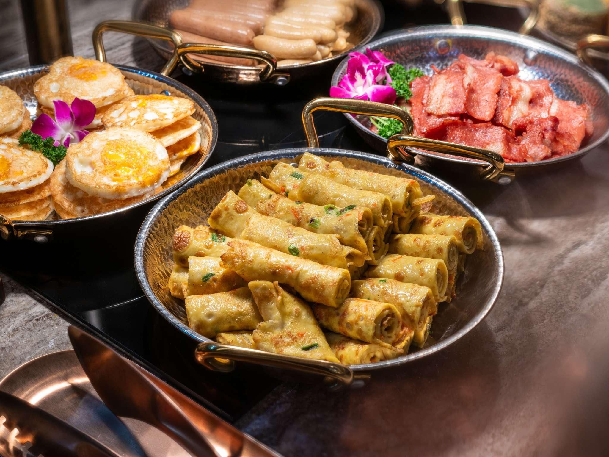 A variety of dishes including fried eggs, spring rolls, and other Asian cuisine.