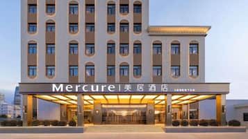 Ein Hotel mit moderner Fassade, mehreren Etagen und einem überdachten Eingangsbereich.