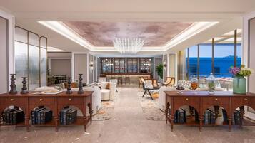 A spacious room with a bar area, seating, and a view of the sea.
