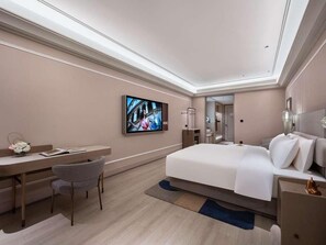 Een moderne hotelkamer met een bed, een bureau, een stoel, een televisie en een badkamer zichtbaar door een geopende deur.