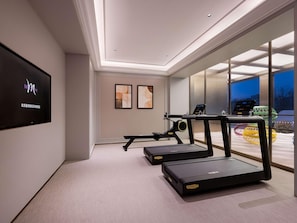 A modern home gym with treadmills, a stationary bike, and a TV displaying a logo. - Mercure Beijing Lize Road (Beijing)