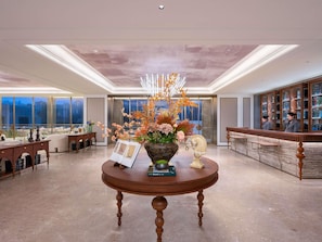 A hotel lobby with a reception desk, a large window, and a decorative table with a vase of flowers. - Mercure Beijing Lize Road (Beijing)