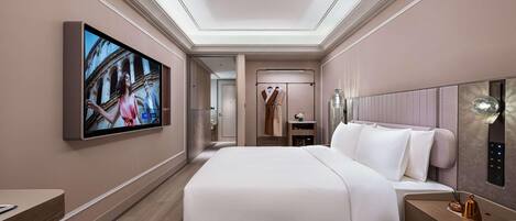 A modern hotel room with a large bed, a TV mounted on the wall, a desk, and a chair.