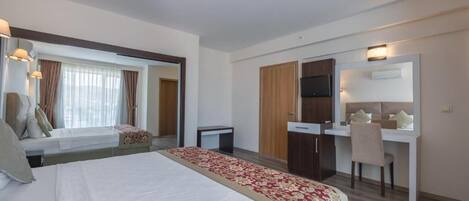 A hotel room with a bed, a desk, a chair, a TV, and a window with curtains.