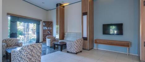 Un salón amplio con sofá, sillas, televisor y banca.
