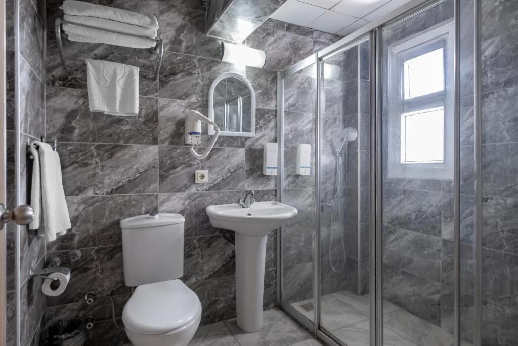 Ein Badezimmer mit Toilette, Waschbecken und einer Duschkabine aus Glas.