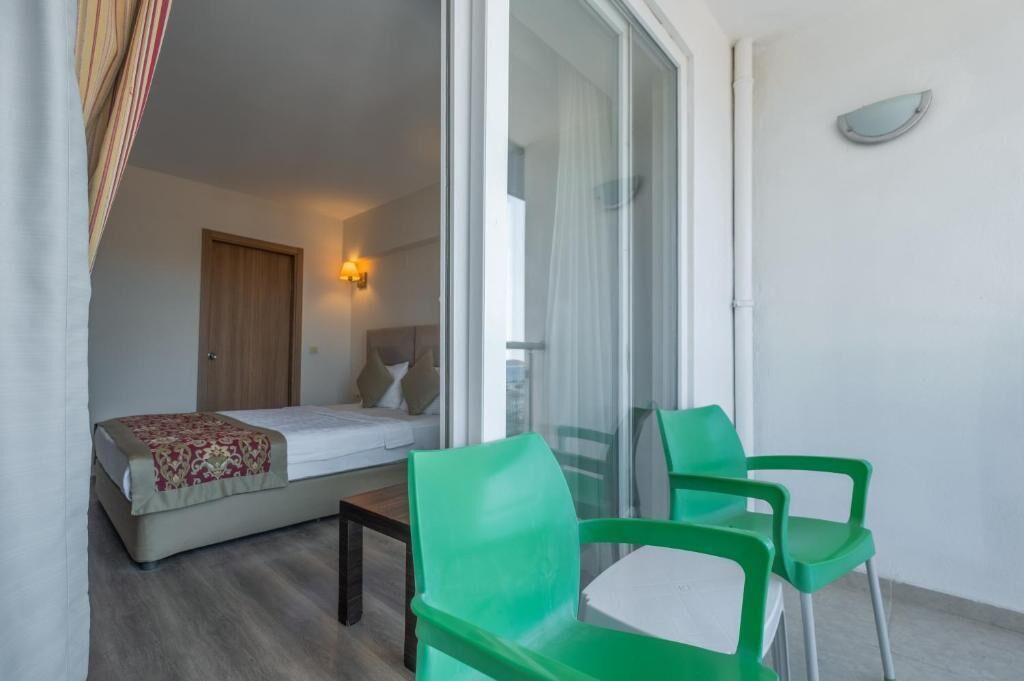 Una stanza con un letto, un tavolino e due sedie verdi.