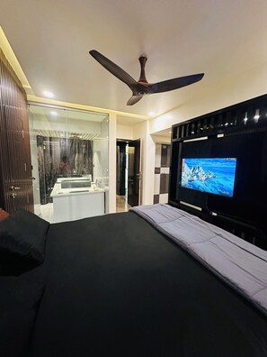 Quarto de hotel moderno com cama, televisão e ventoinha no teto.