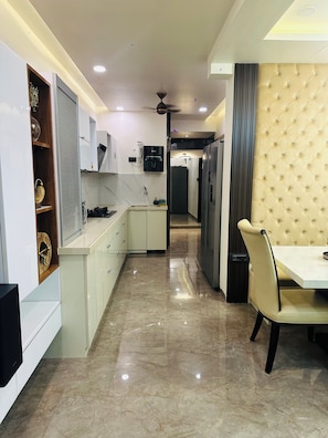 A modern kitchen with a marble floor, built-in cabinets, and a dining area with a tufted headboard.