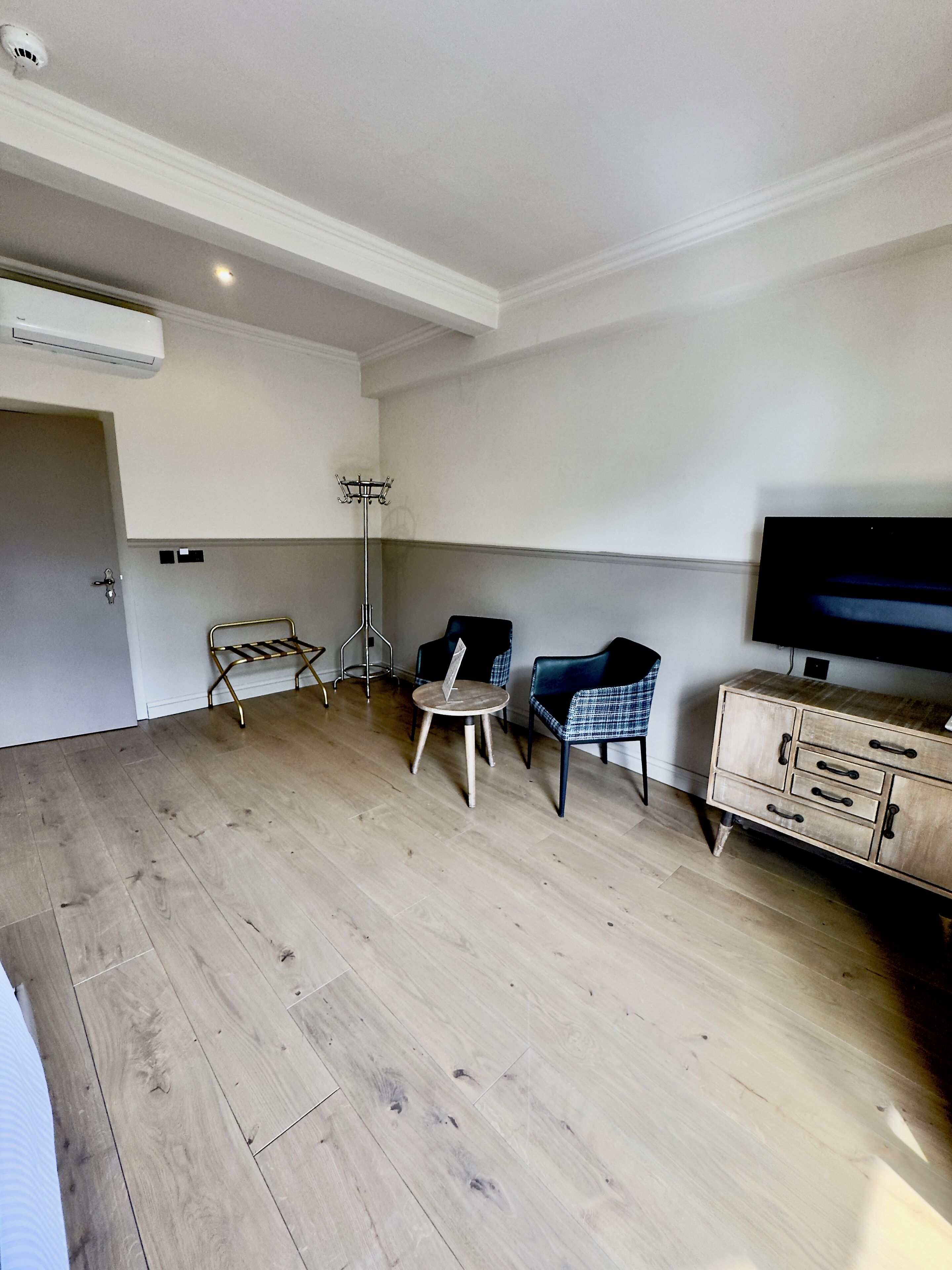 Une pièce équipée d’un téléviseur à écran plat, d’une armoire en bois, d’une chaise, d’une petite table et d’un lampadaire.