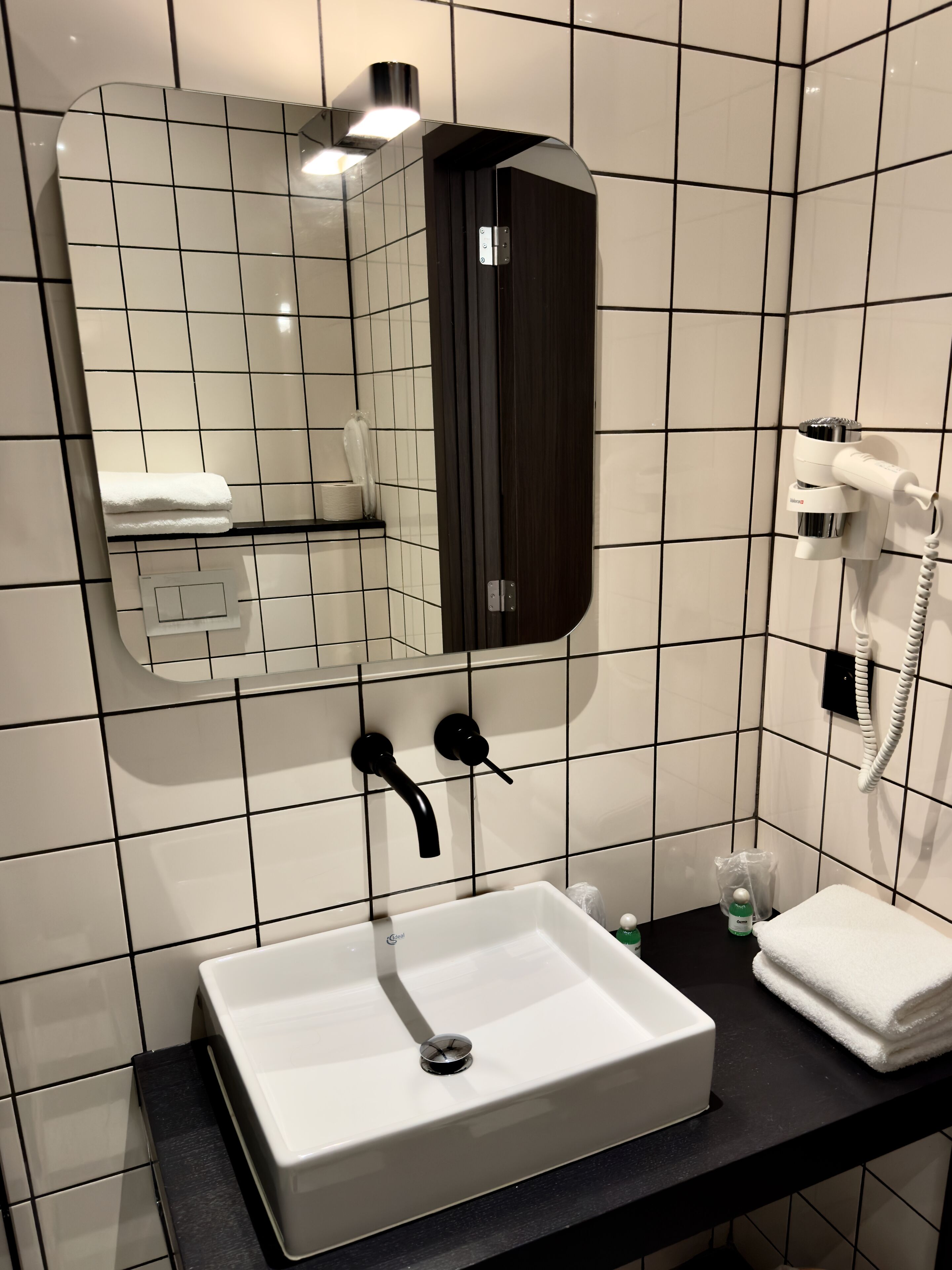 Een badkamer met een wit wastafel, een spiegel, een handdoek en een haardroger.