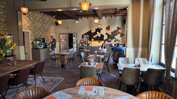 L’intérieur d’un restaurant, avec des tables et des chaises en bois, ainsi que des lampes suspendues.