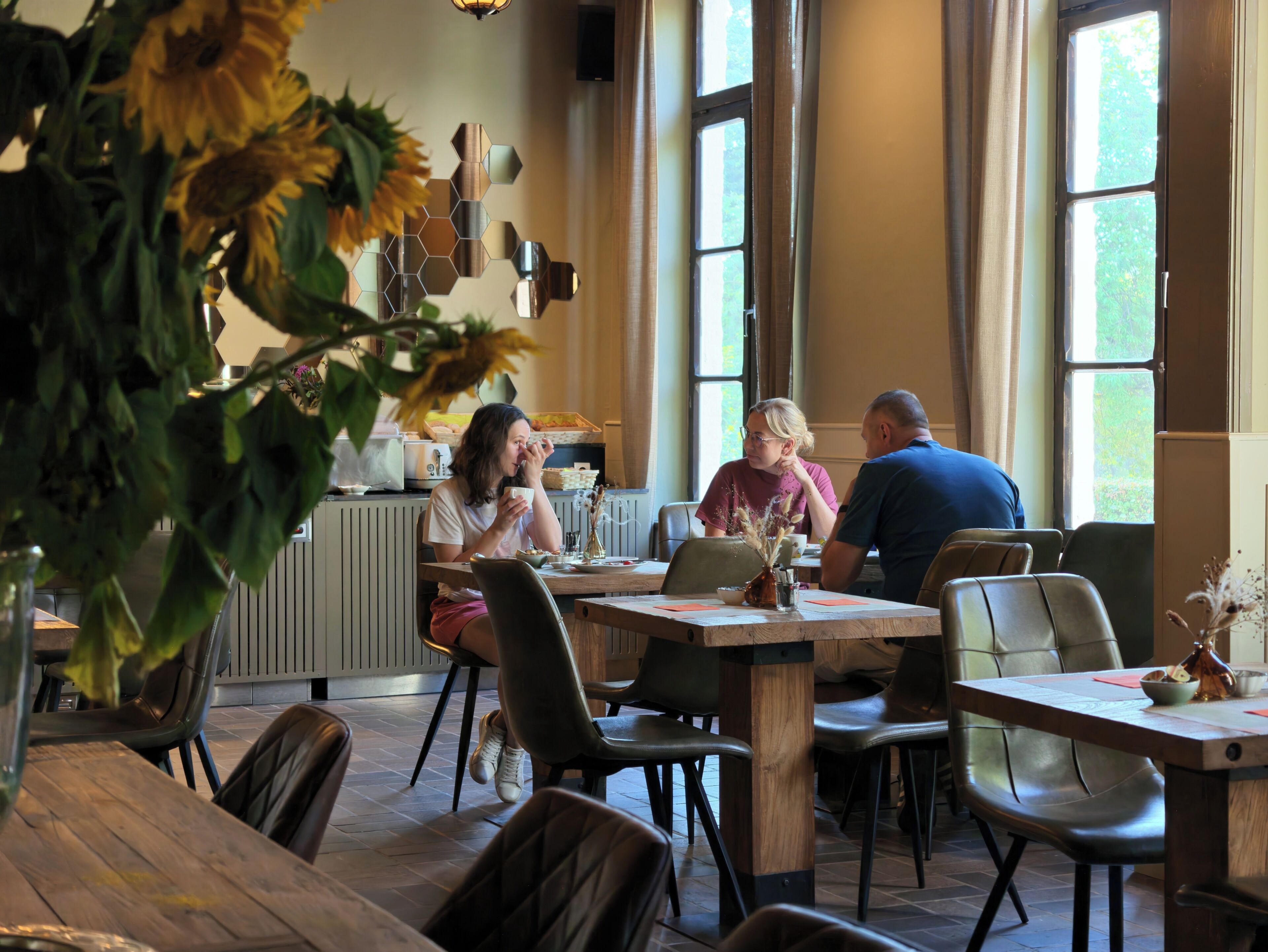 Un coin repas avec une table en bois, des chaises et un vase rempli de tournesols.