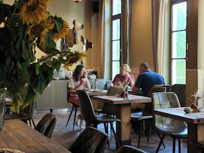 A dining area with a wooden table, chairs, and a vase of sunflowers.