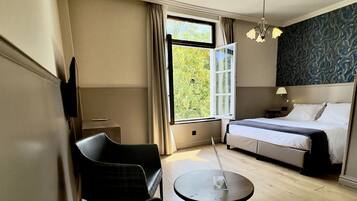 A hotel room with a bed, a sofa, a dining table, and a chair.