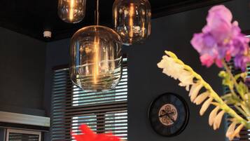 A modern interior with pendant lighting, a wall clock, and a window with blinds.