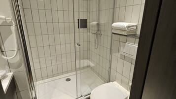 A modern bathroom with a glass-enclosed shower, a toilet, and a checkered floor.