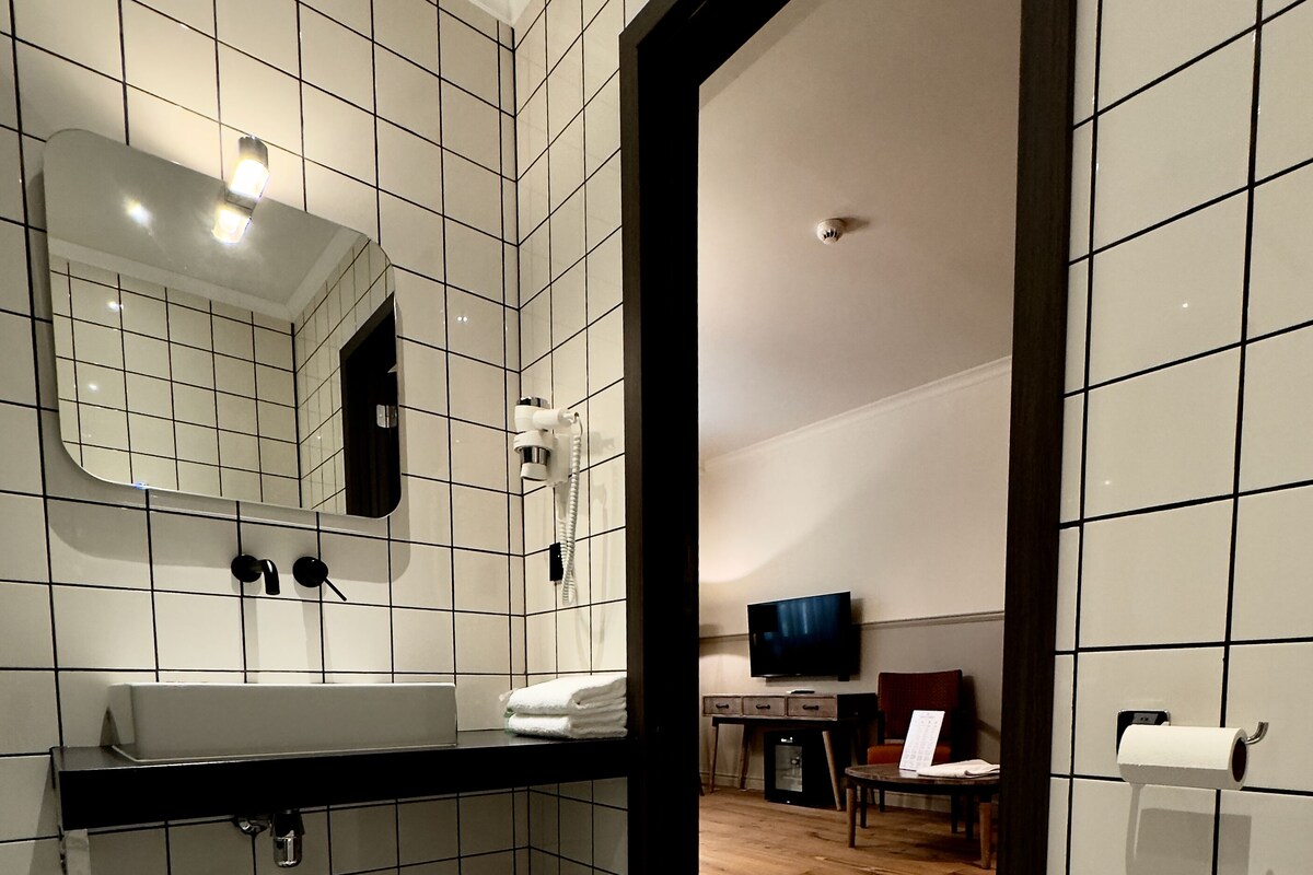 A modern bathroom with a black and white checkered floor, a white toilet, a sink with a mirror, and a shower area.