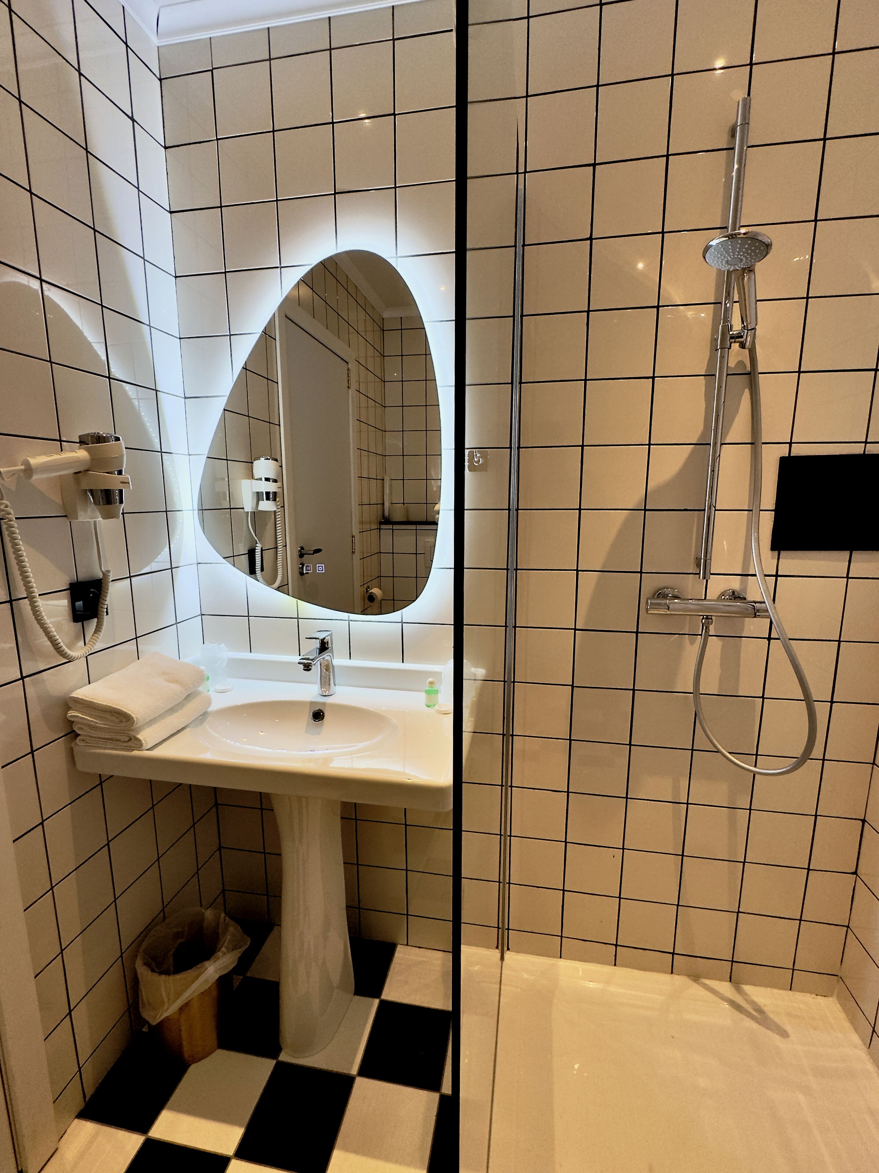 Un baño con lavamanos blanco, espejo y ducha.