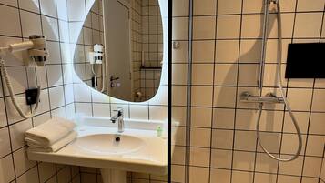 Un baño con lavamanos blanco, espejo y ducha.