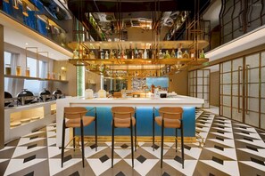 Eine Bar mit einer Theke, Hockstühlen und Regalen voller Flaschen.