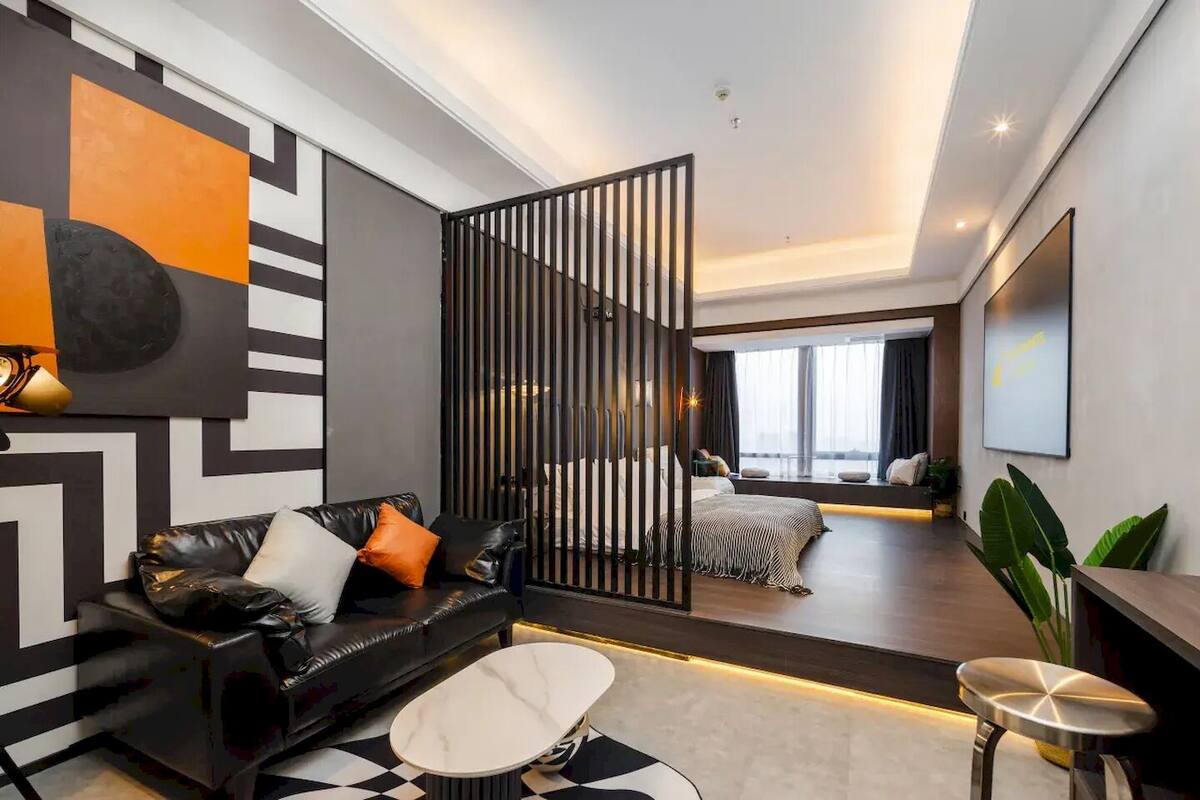 Moderni hotellihuone, jossa on kulmasohva, näköalalla varustettu sänky, ruokailutila ja suuri ikkuna.