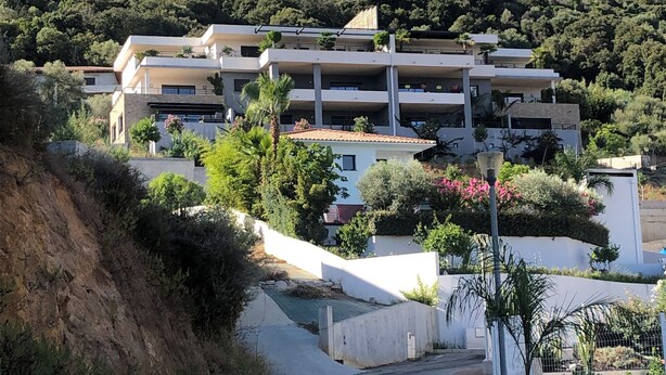 A multi-story building with a modern architectural style, surrounded by greenery and hills. - Between sea and mountains, spacious, quiet apartment with superb views. (Alata)