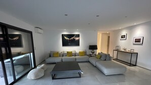 A modern living room with a sectional sofa, a coffee table, and a glass door leading to a balcony. - Between sea and mountains, spacious, quiet apartment with superb views. (Alata)