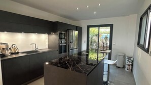 A modern kitchen with a central island, built-in appliances, and a view to the outdoors. - Between sea and mountains, spacious, quiet apartment with superb views. (Alata)