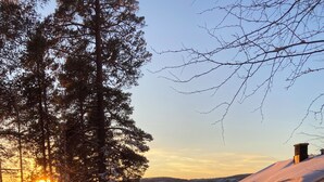 Un paysage enneigé avec un chalet en bois, un ciel dégagé et un coucher de soleil.
