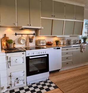 A kitchen with white cabinets, a black oven, and a checkered floor. - Unique accommodations close to nature in northern Sweden (Gran)
