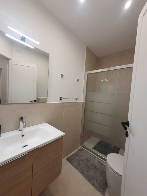 A modern bathroom with a white sink, mirror, and shower.