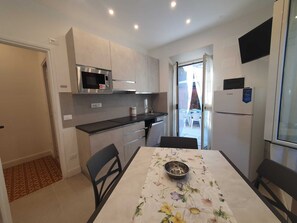 A compact kitchen with a microwave, refrigerator, and dining table with chairs. - Oasis of Peace: three-room apartment with private garden a few steps from the sea (Fregene)