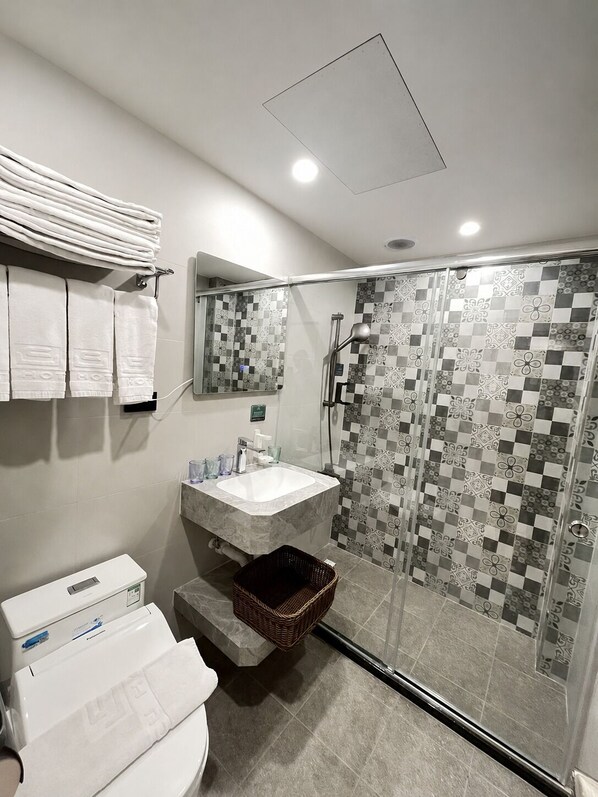 A bathroom with a toilet, sink, and shower area. - Tongcheng Fudelai Grand Hotel (Tainan)