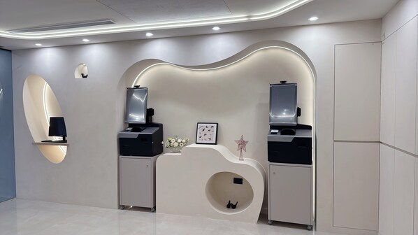 A modern, minimalist room with a curved reception desk, two wall-mounted monitors, a framed picture, and a decorative star. - Tongcheng Fudelai Grand Hotel (Tainan)