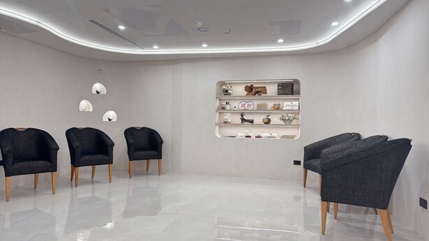 A modern interior with a white wall, a shelf with decorative items, and four dark armchairs. - Tongcheng Fudelai Grand Hotel (Tainan)