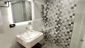 A modern bathroom with a glass-enclosed shower, a white sink, and a mirror above it. - Tongcheng Fudelai Grand Hotel (Tainan)