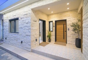 Fachada de piedra con dos puertas, una planta en maceta y un acceso con baldosas.
