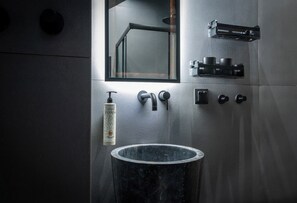 A modern bathroom with a marble sink, a bottle of hand soap, and a mirror. - A modern apartment in the center of discreet luxury and comfort 30m from the sea (Ierapetra)