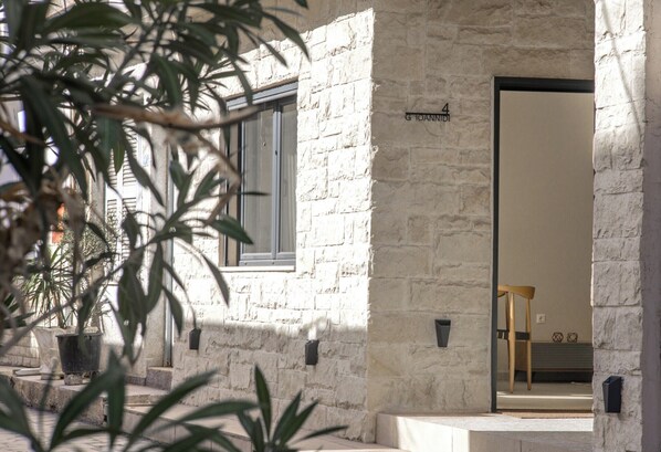 A stone building with a door, potted plants, and a bench.