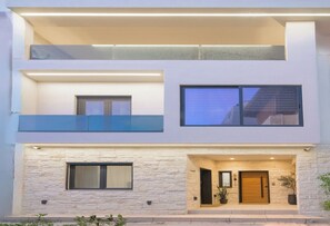 Un edificio moderno de dos pisos con fachada de piedra, ventanas grandes y un balcón.