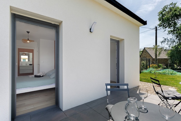 A modern room with a bed, a table with chairs, and a glass of water.